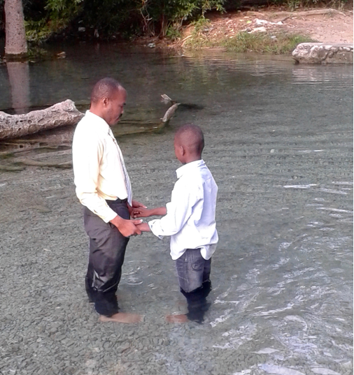Opettajapastori kastaa pienen uskoontulleen koulupojan