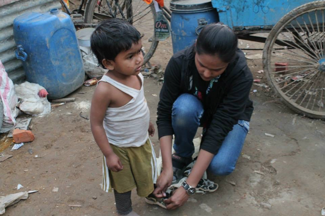 Vaatteiden jakoa Intiassa. Sovitetaan kenkiä slummin lapsille.